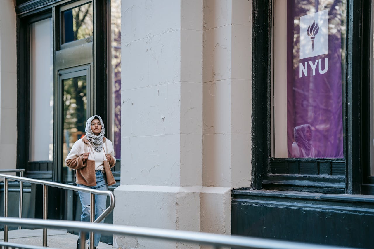 Crafting Captivating Headlines: Your awesome post title goes here Young Muslim woman walking outside NYU, showcasing urban lifestyle and fashion.